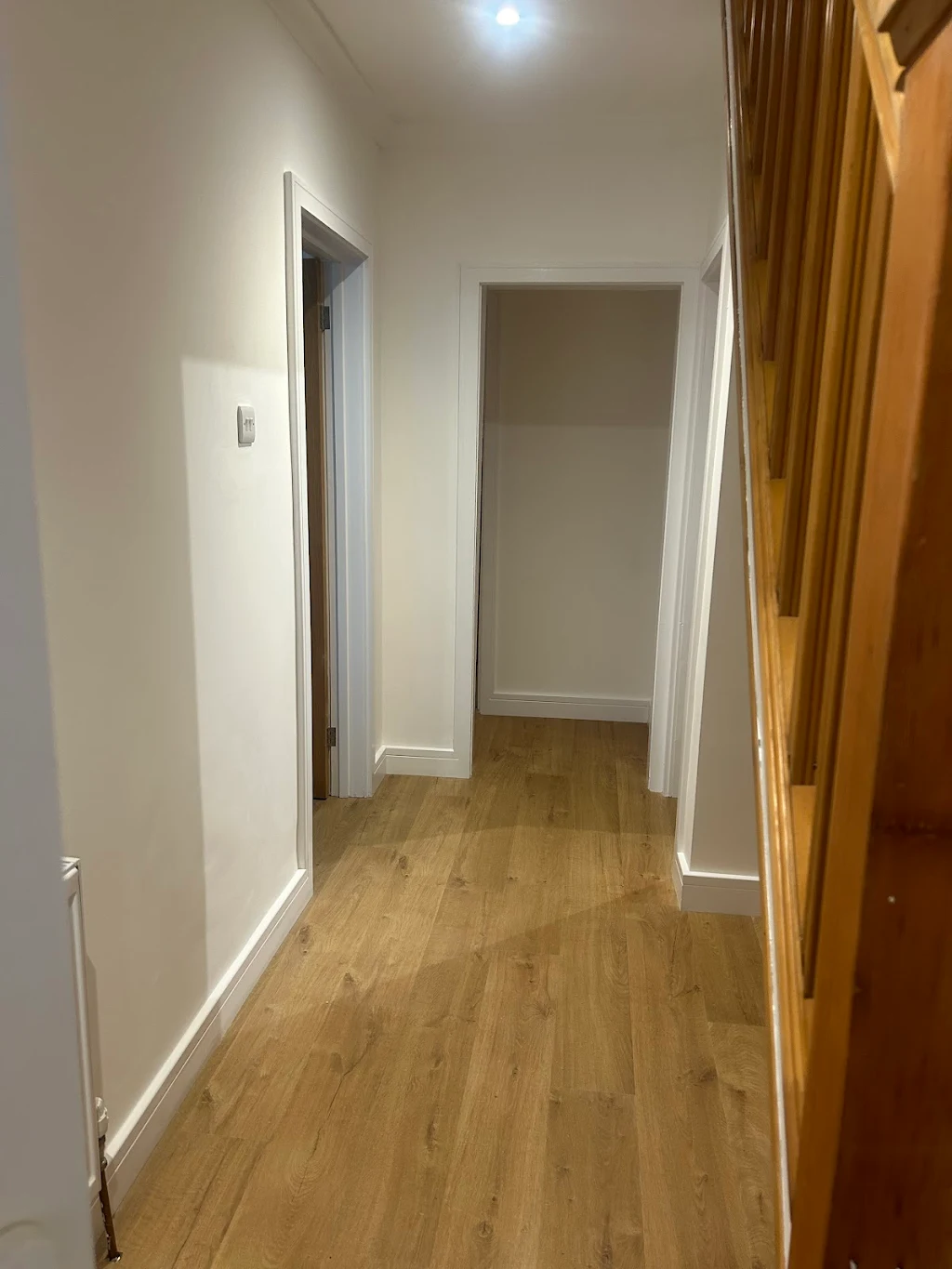 Modern hallway with white doors and wooden flooring