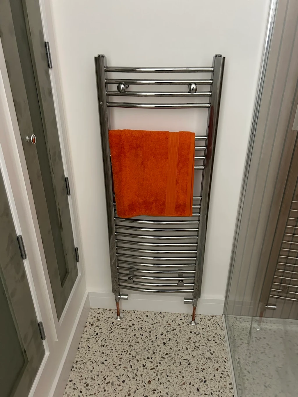Chrome towel rail with orange towel in bathroom