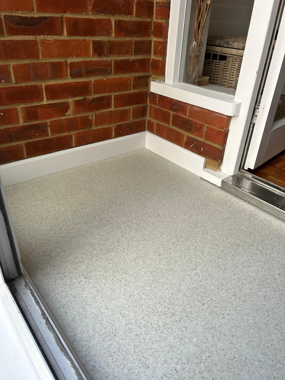 New porch flooring and white skirting against the brick wall and window