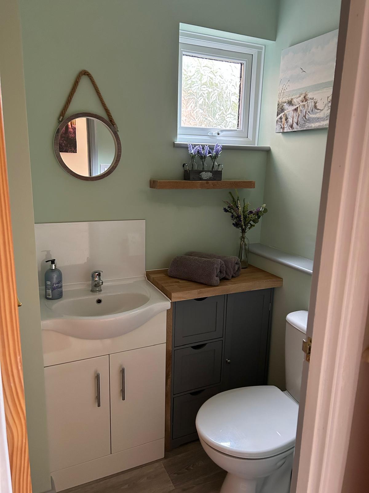 Completed understairs cloakroom with basin vanity unit and toilet